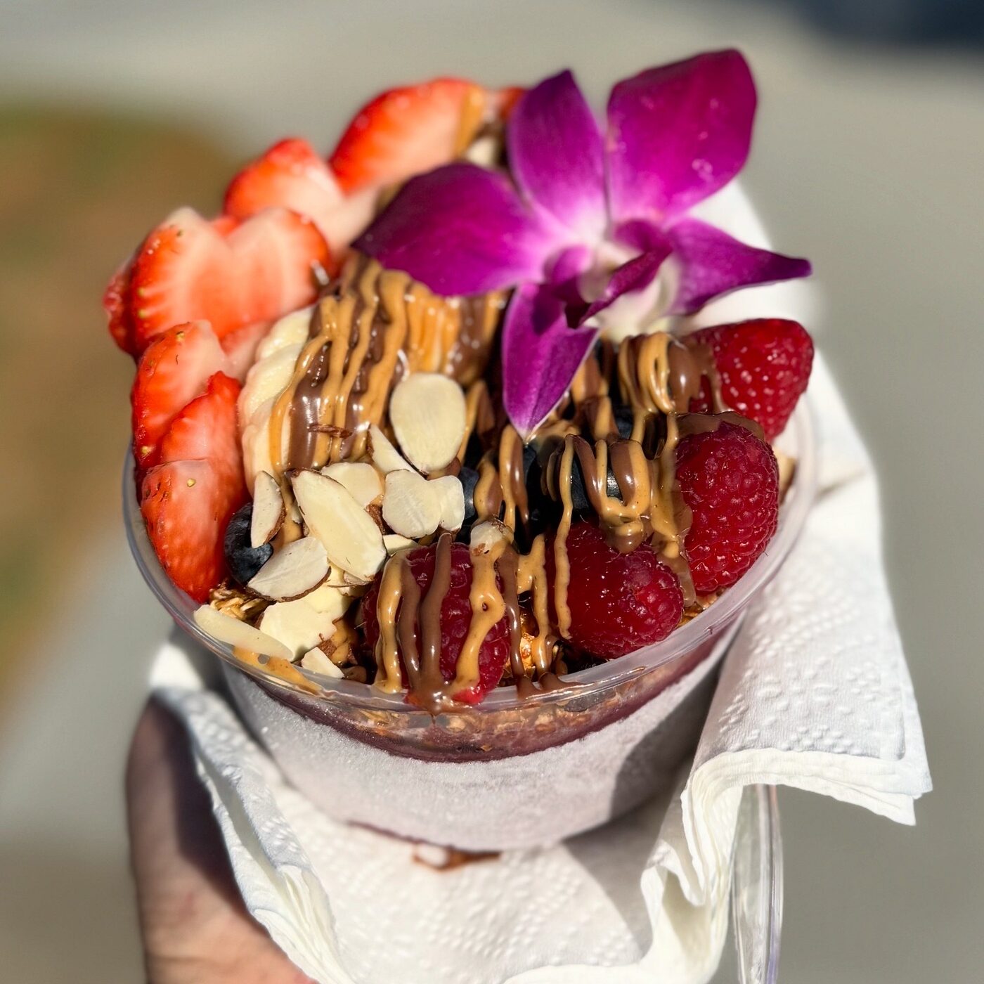 Açaí bowl topped with fresh berries, almonds, and an orchid