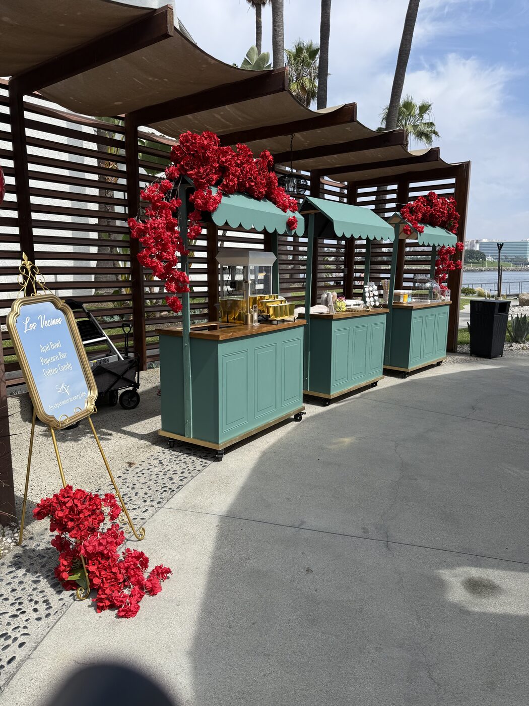 Three Los Vecinos carts dressed in red florals at a waterfront event