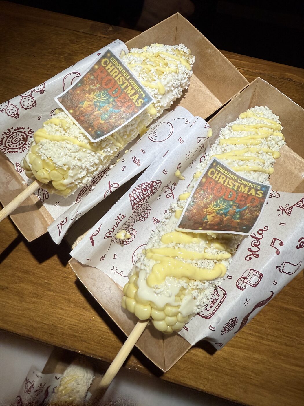 Corn on the cob with crema and cheese, finished with custom edible event toppers